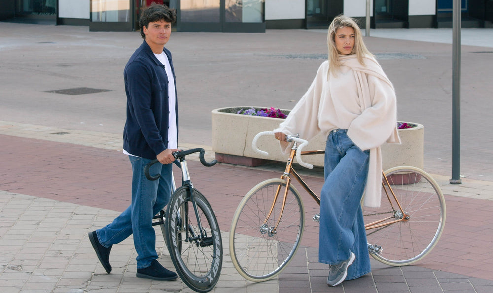 Two people with bicycles on a city street.